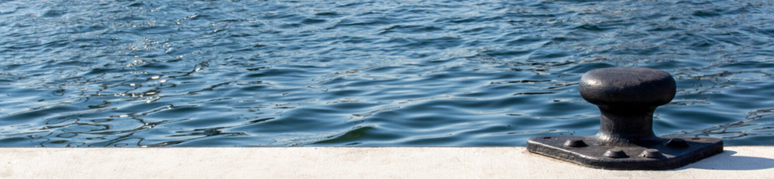 bollar on pier with blue sea water in background