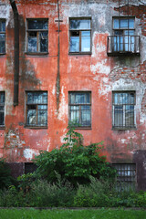 Fototapeta na wymiar An old abandoned house with red cracked paint. Facade with windows.