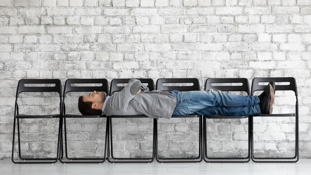 Bored Exhausted Candidate Applicant Businessman With Arms Crossed Lying On Office Chairs In Empty Office Hall, Job Seeker Waiting For Interview Too Long, Employment And Recruitment Process