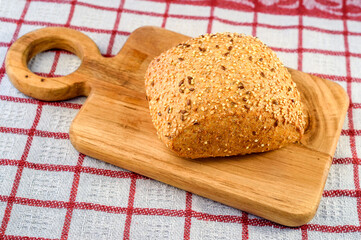 Rustic bread with sesame and flax seeds on the wooden cutter