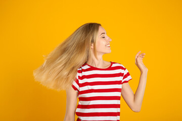 Portrait of beautiful young woman with blonde hair on yellow background