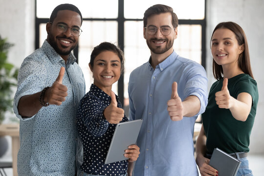 Smiling diverse employees team showing thumbs up, looking at camera, happy overjoyed colleagues recommending best corporate service, good career, human resources and employment concept
