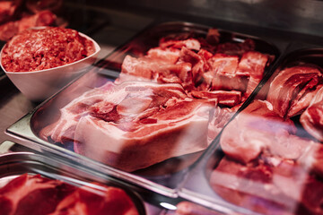 Raw meat in meat shop counter. Different fresh and uncooked products selling.