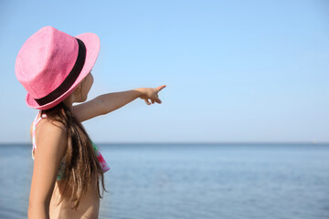 Cute little child pointing at something in sky. Beach holiday