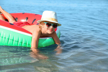 Cute little child with inflatable ring in sea on sunny day. Beach holiday