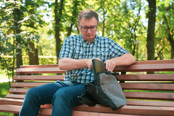 Fototapeta premium The guy sits in the park and works at a laptop.