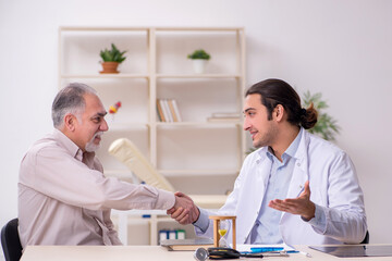 Obraz premium Old male patient visiting young doctor in time management concep