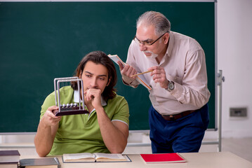 Old professor physicist and young student in the classroom