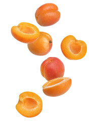 Cut and whole ripe apricots falling on white background