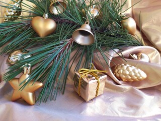 Naklejka na ściany i meble Fresh green pine branch with colden christmas toys on a golden background