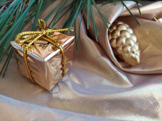 Fresh green pine branch with colden christmas toys on a golden background