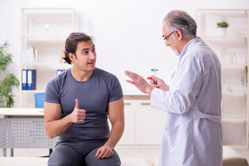 Obraz premium Young male patient visiting old doctor traumatologist