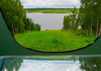reflection and view from camping tent  on the river bank in a picturesque landscape