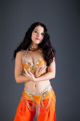 closeup portrait of beautiful brunette girl poses in orange belly dancer costume