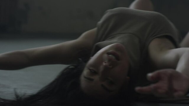 Contemporary dancer falls and rolls on the ground in industrial warehouse