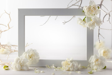 Still life with white flowers and frame on light backdrop. Creative concept for celebration of...