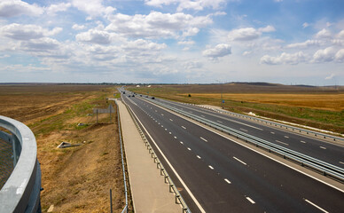 highway in steppe against a blue sky,long road stretching out into the distance.