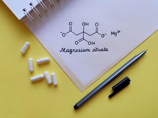 Structural chemical formula of magnesium citrate molecule with white pills. Magnesium citrate is a...