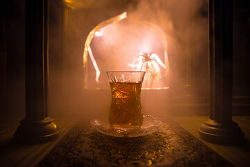 Arabian tea in glass inside room. Low light lounge interior with carpet. Selective focus