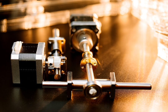 motor and guides for the laser machine. details of the engraving machine, black warm background, orange light.