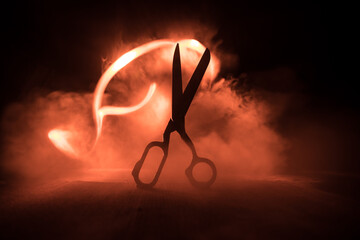 Old tailor`s scissors on wooden table in low light. Artwork decoration with toned foggy backlight....