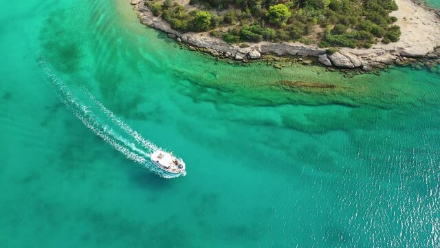 Aerial bird's eye view video taken by drone of boat cruising in Caribbean tropical rocky beach with turquoise - sapphire waters