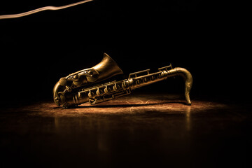 Alto gold sax miniature with colorful toned light on foggy background. Saxophone music instrument...
