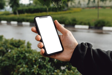 Mockup image of hand holding mobile phone with blank white screen. A man with a smartphone against...