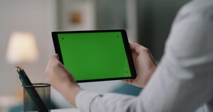 Close up shot of man holding a tablet computer with green screen. Guy working or watching a webinar, attending online video conference, staying at home. c 4k footage