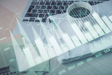 Double exposure of forex chart drawing and desktop with coffee and items on table background. Concept of financial market trading