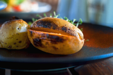 Baked spicy potatoes on plate, close up. Selective focus. Horizontal image.