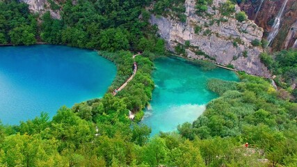 The National Park of Plivice Lakes in mountain Krast in Croatia. The aerial view of board walk on waterfall cascade of Plitvice Lakes, the UNESCO World Heritage. Travel destination for turists.