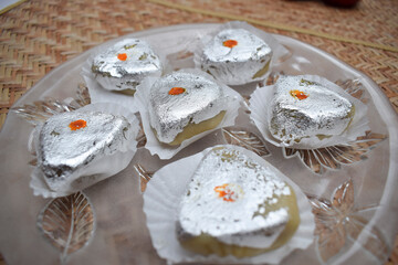 Indian or Pakistani sweet selective focus with silver vark or silver edible foil Kaju barfi peda khoya served in transparent plate