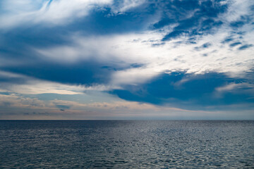 Fototapeta premium Dark grey-blue stormy clouds over the sea, patch of clear sky in the distance