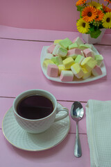 Cup of coffee in the morning on pink wooden table and delicious marshmallows. The concept of romatics breakfast, tenderness, good morning