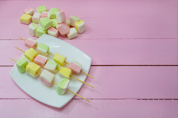 Marshmallows on skewers. Pink wood background, copy space. Light dessert, sweets, tenderness