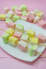 Marshmallows on white dish. Pink wooden background. Dessert for holiday