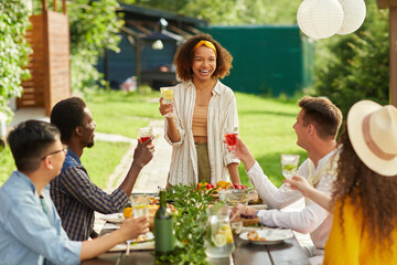 Portrait of young African-American woman laughing cheerfully while enjoying dinner with friends at outdoor terrace in Summer, copy space - obrazy, fototapety, plakaty