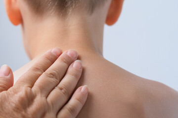 female hand gently lubricates the back of a child, boy 6-7 years old with sunscreen, body hygiene...