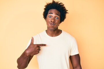 Handsome african american man with afro hair pointing with fingers to himself puffing cheeks with funny face. mouth inflated with air, catching air.