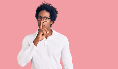 Fototapeta na wymiar Handsome african american man with afro hair wearing casual clothes and glasses asking to be quiet with finger on lips. silence and secret concept.