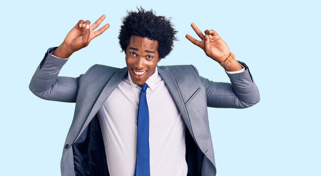 Handsome african american man with afro hair wearing business jacket posing funny and crazy with fingers on head as bunny ears, smiling cheerful
