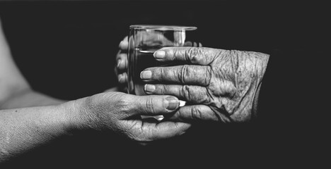 Fototapeta premium Water in hands, helping the elderly, black and white photo