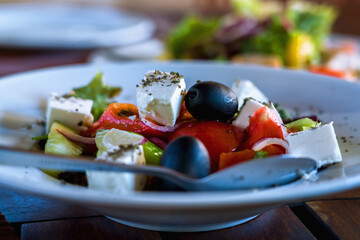 A Caesar salad on white plate on dark wooden table. Selective focus.