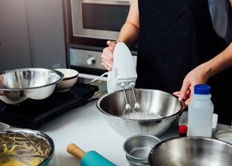 Woman beat dough mixer by machine in bowl at her kitchen
