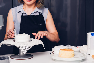 Woman during decorating cake with cream at homemade