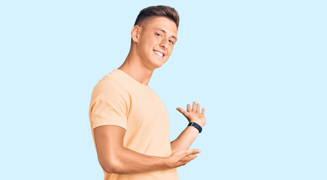 Young handsome man wearing casual clothes inviting to enter smiling natural with open hand