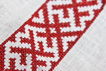 embroidery with a cross with red nicknames on linen