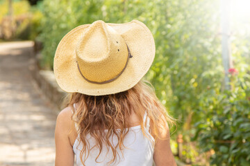 woman in hat in summer outdoors from behind