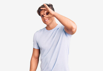 Naklejka premium Young handsome man wearing casual clothes smiling happy doing ok sign with hand on eye looking through fingers